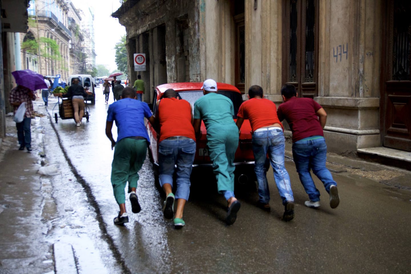 Men pushing a broken car in Havana. Daily life in Cuba.
