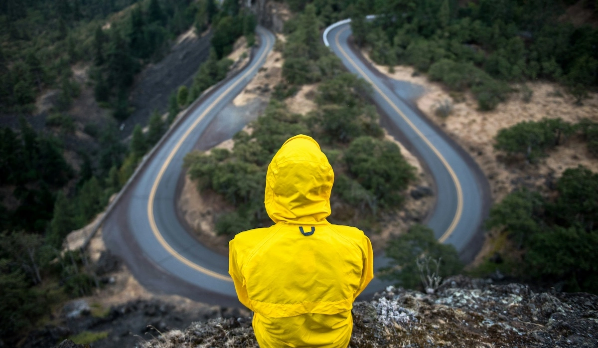 Traveler standing at a literal crossroads, looking thoughtfully at diverging paths, symbolizing adaptability, courage, and open-mindedness