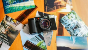 Vintage film camera surrounded by scattered travel photographs and orange film strips, creating a nostalgic collage of travel memories
